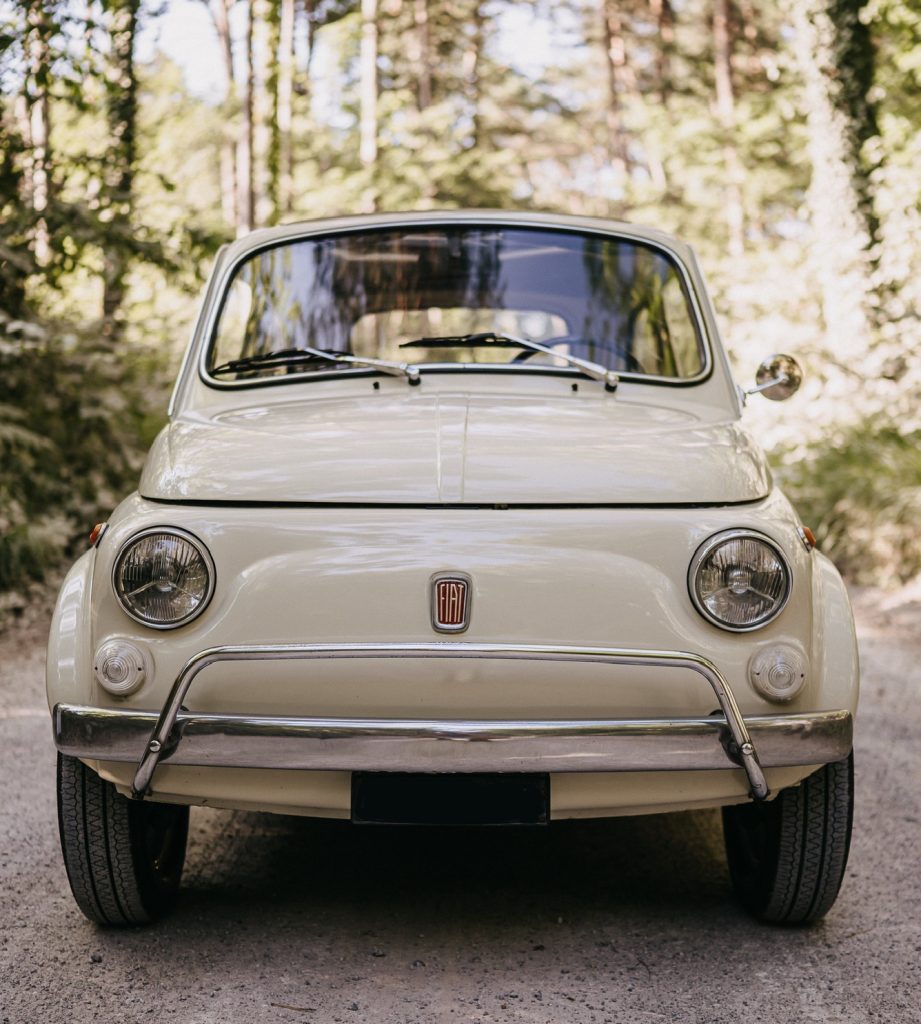 Fiat 500L color avorio, vista frontale su una strada di campagna alberata