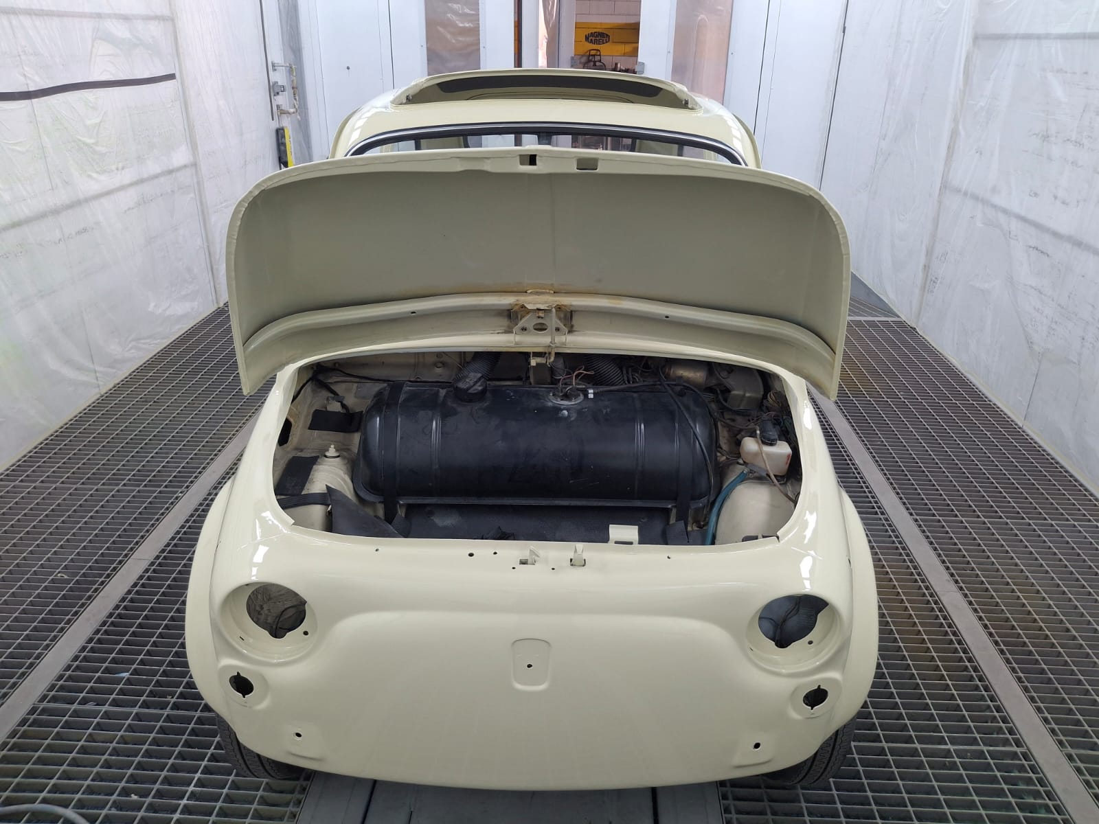 Fiat 500L durante il restauro, con il vano motore aperto in cabina di verniciatura