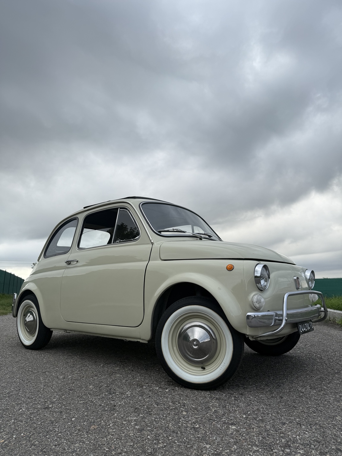 Fiat 500L color avorio restaurata, vista tre quarti anteriore con cielo nuvoloso